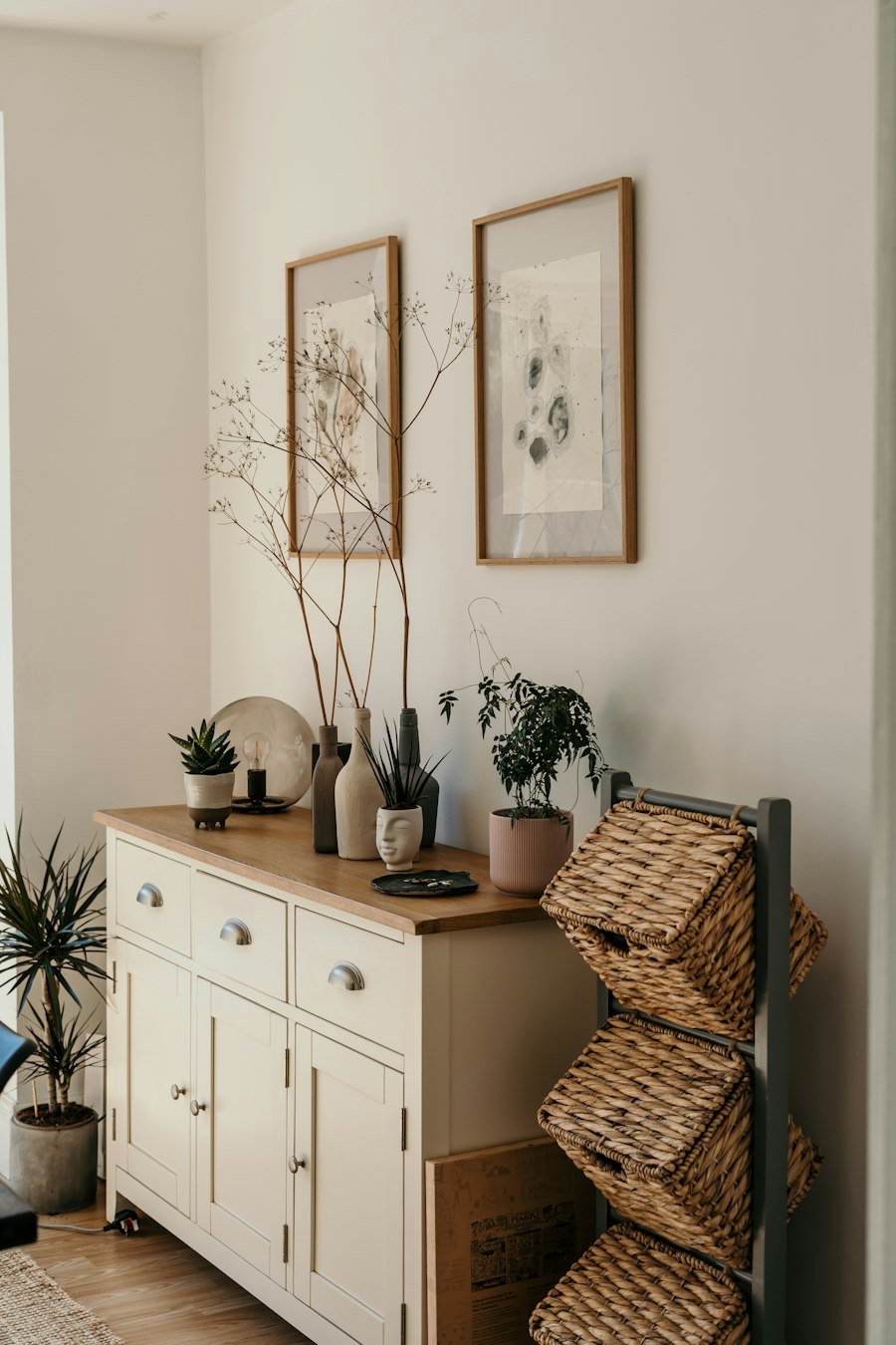 Styled console with framed art and plants against a neutral wall